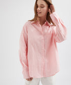 Woman wearing a pink button-up shirt against a white background