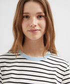 Person wearing a black and white striped shirt with a light blue collar on a plain background