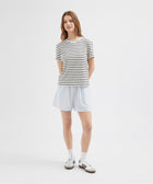 Person wearing a striped shirt and light blue shorts on a white background
